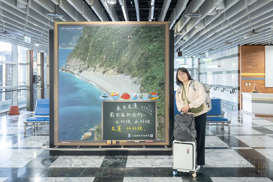 Kay 在花蓮機場大廳的清水斷崖造景看板前合影