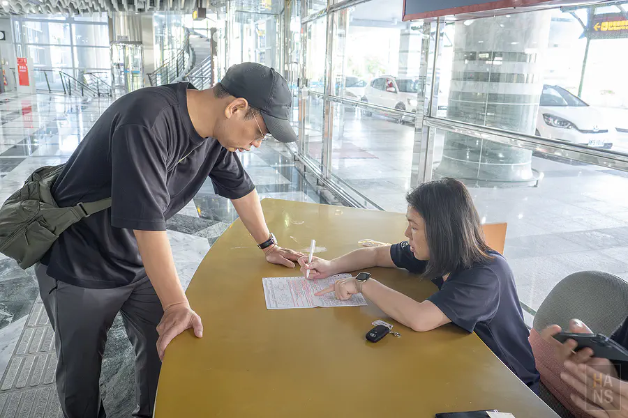 翰斯在 IWS 愛旺租車櫃檯簽署租車合約