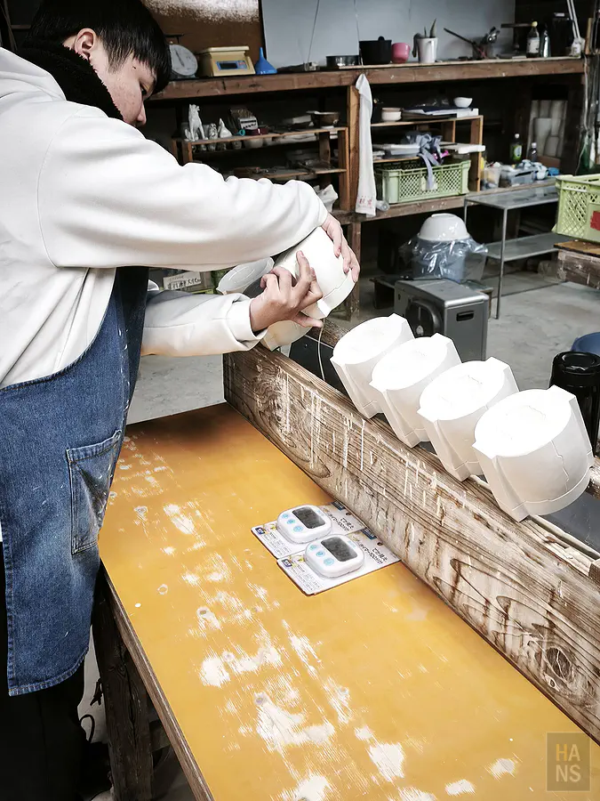 年輕職人熟練地操作模具將多餘泥漿倒出