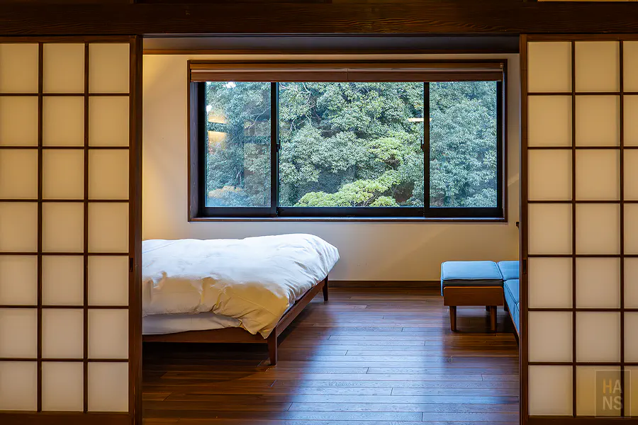 從和室看往臥室洋床與綠意窗景的視角