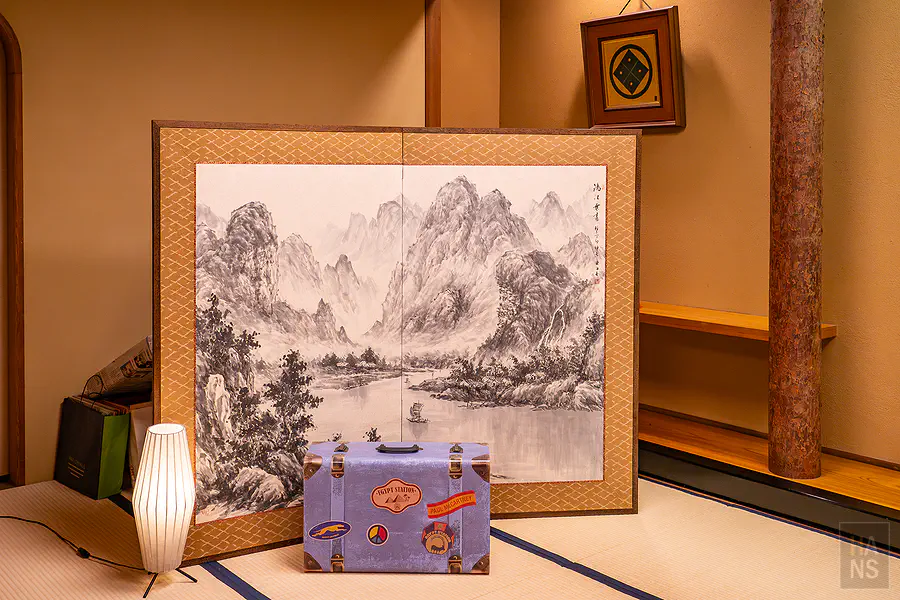 水墨畫屏風與復古搖滾貼紙行李箱的奇妙組合