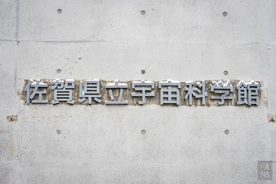 清水模牆面上的佐賀縣立宇宙科學館金屬字樣標誌