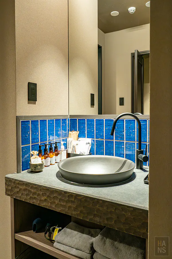 衛浴空間深邃的蔚藍色磁磚牆面搭配消光黑現代水龍頭與質感石材檯面