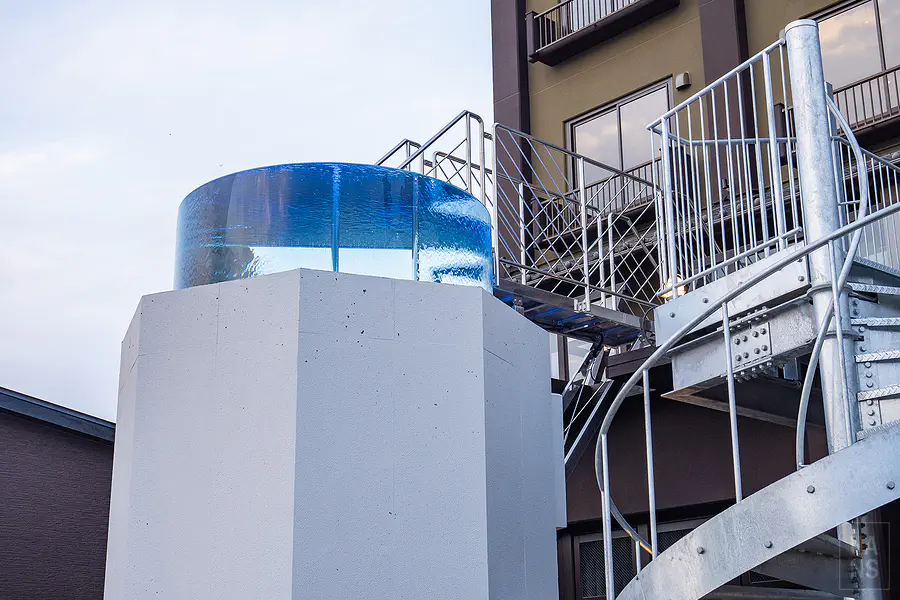 頂樓戶外透明壓克力水風呂在白天陽光照射下呈現清涼的湛藍色澤