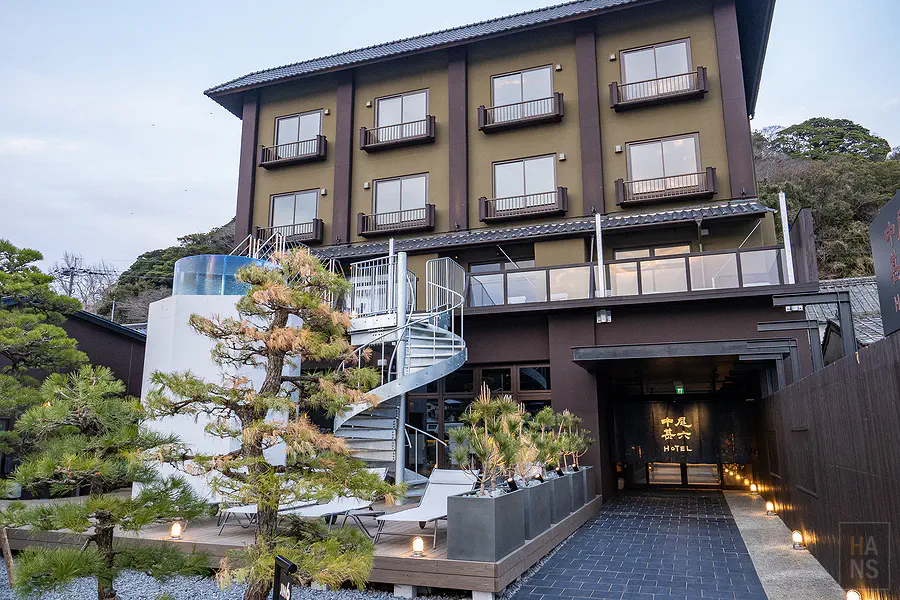 傍晚時分的中尾甚六HOTEL本館外觀與入口處精心佈置的松樹盆景及暖色照明