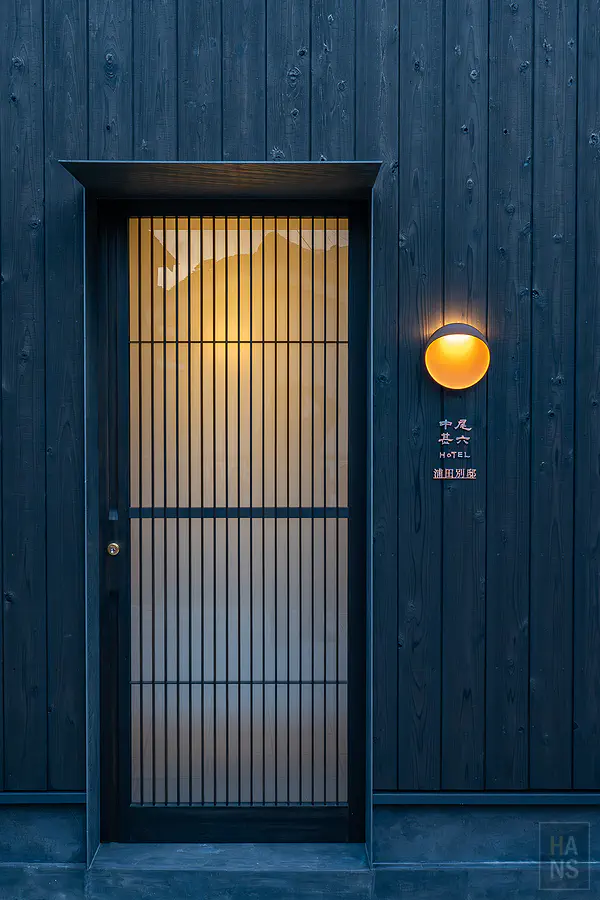 浦田別邸高雅的深色木作大門與透著溫馨暖光的直條柵欄設計