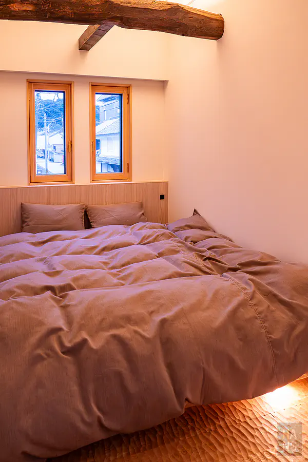 浦田別邸二樓保留原始粗獷大樑與舒適低床架設計的溫馨雙人臥室