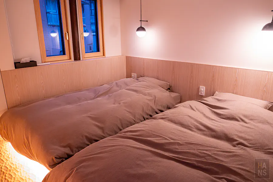 臥室內柔軟厚實的雙人床鋪與散發溫潤質感的木質空間設計