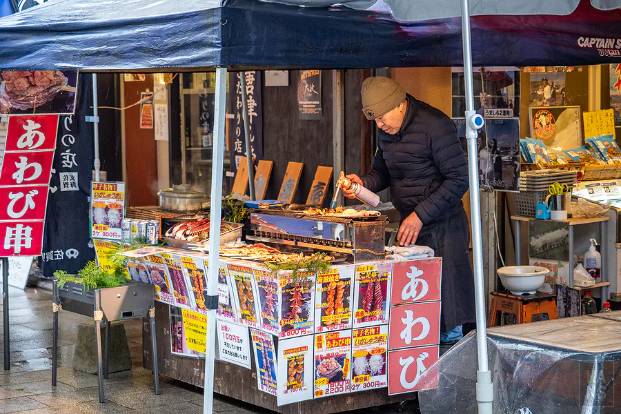 呼子朝市攤販老闆正熟練地使用噴槍炙烤新鮮海鮮串