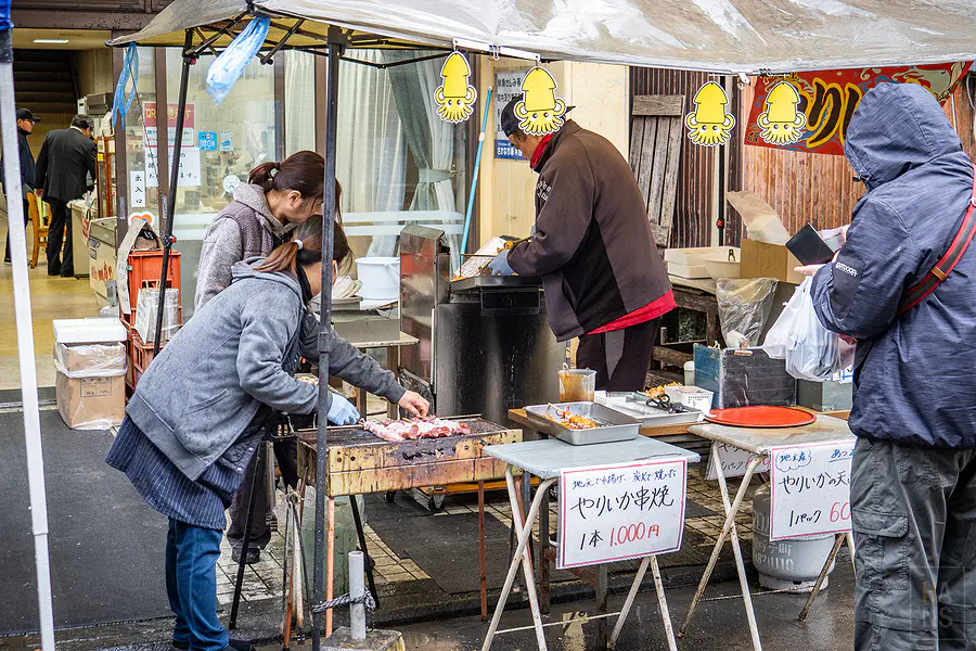 遊客在呼子朝市攤位前等待現烤的美味烏賊串燒