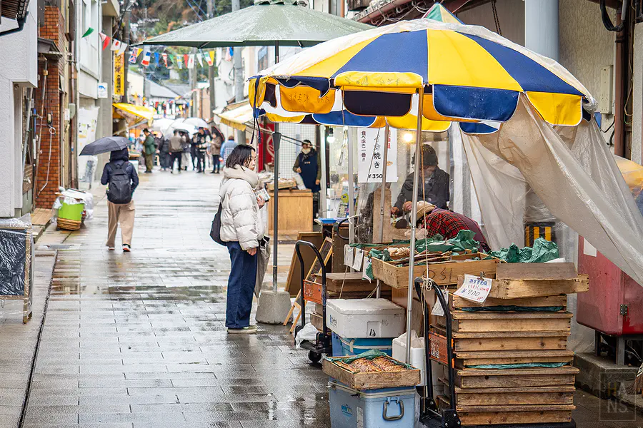 搭著彩色遮雨傘的呼子朝市攤販與微濕的石板路