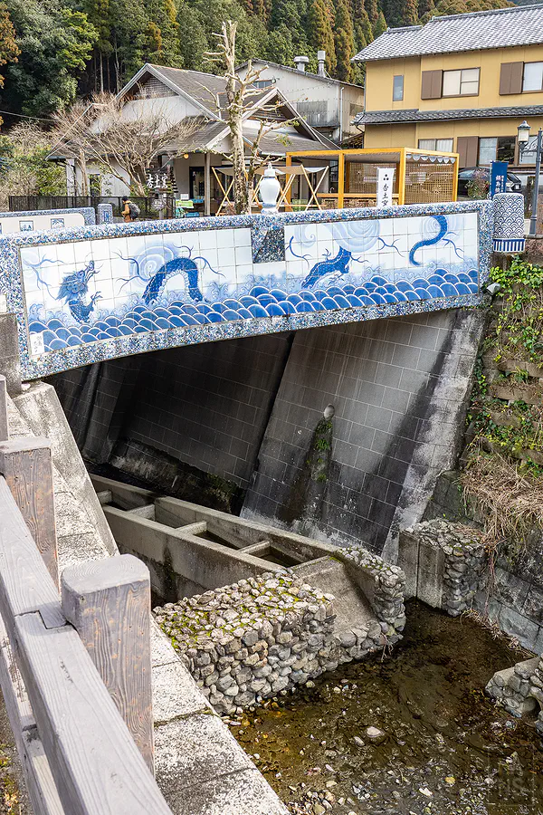 鍋島藩窯橋側面鑲嵌的青龍海浪陶瓷壁畫與潺潺溪流