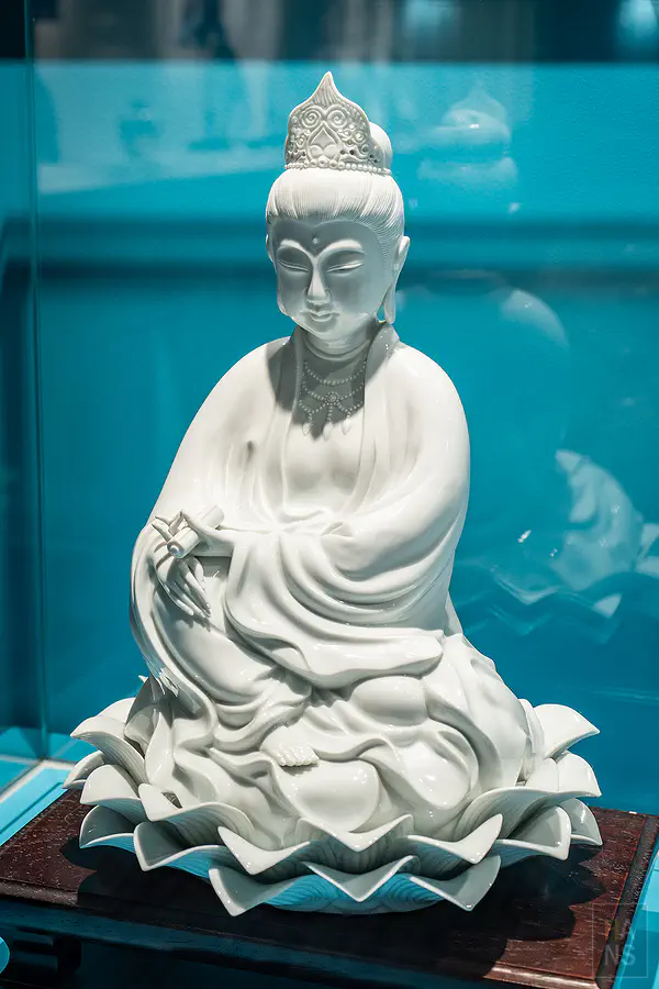 神態莊嚴且衣紋流暢的白瓷觀音坐蓮雕像