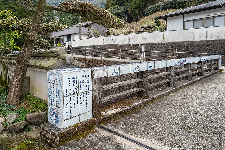大川內山小橋側邊鑲嵌著梅花圖樣的陶瓷板與詩詞
