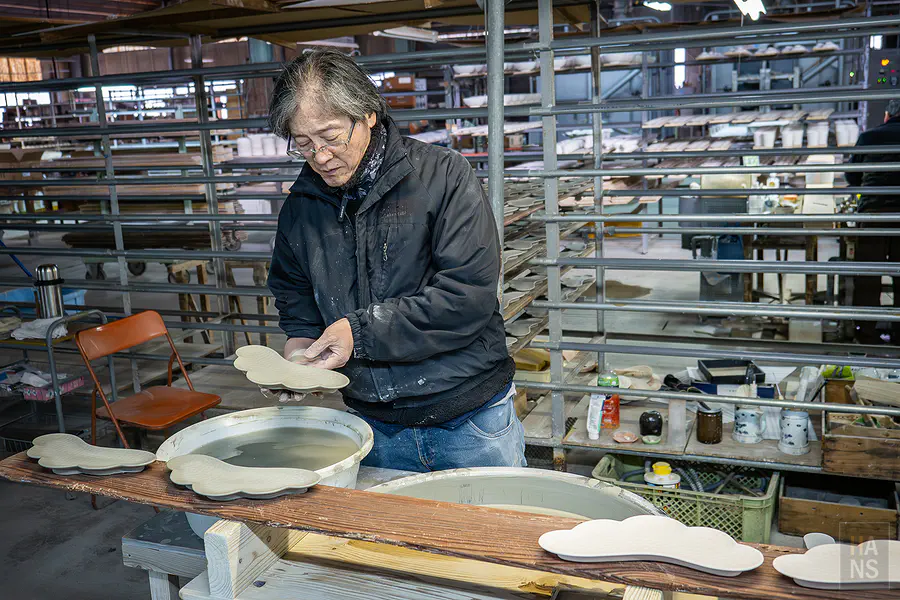 正在修整特殊雲朵造型瓷盤邊緣的專注職人