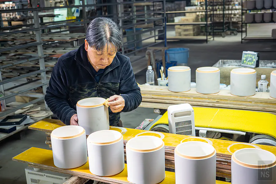 職人專注地為圓筒狀瓷器進行作業
