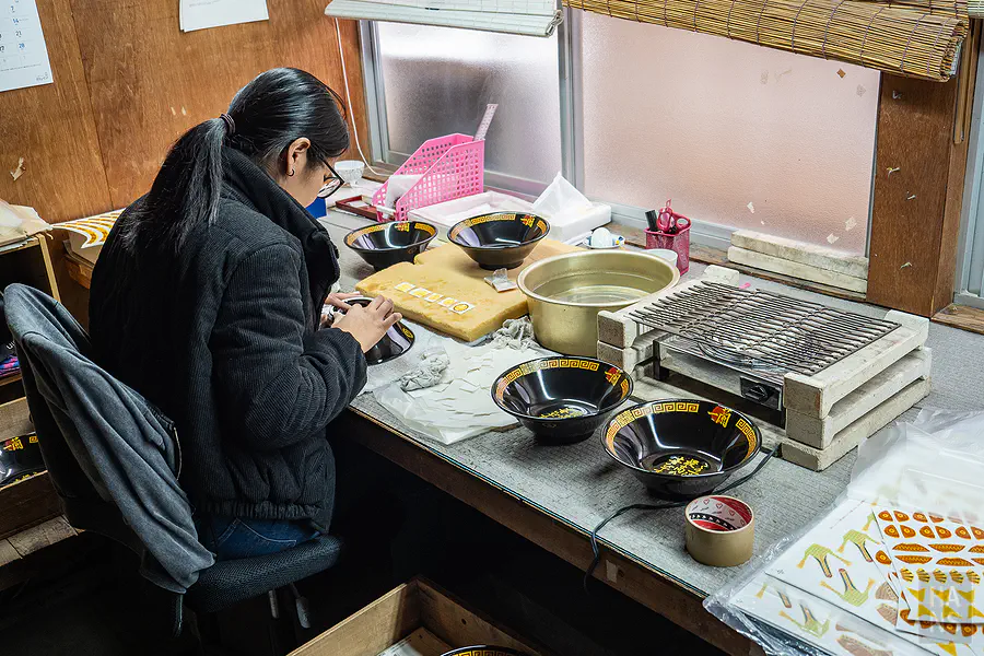 職人小心翼翼地將圖案貼花轉印至一蘭拉麵碗上