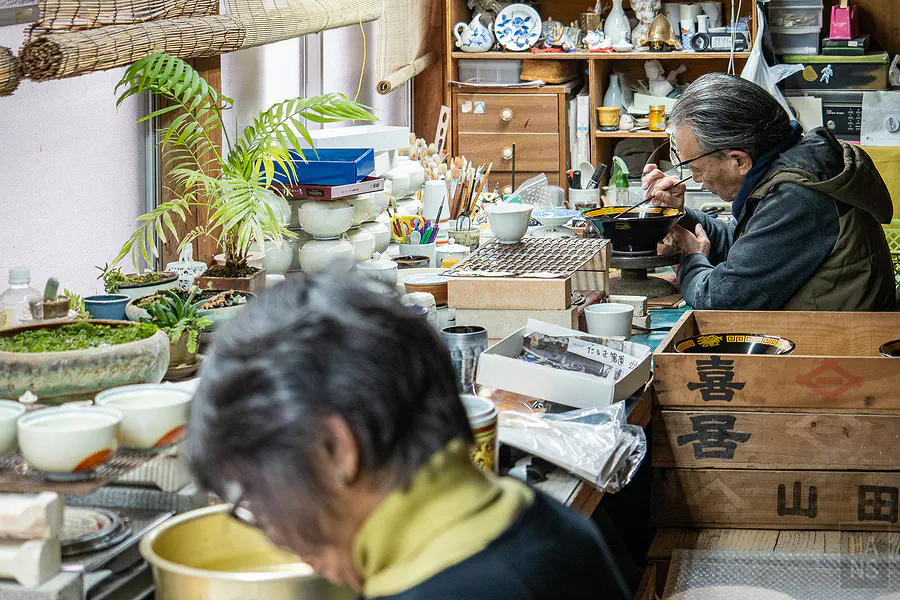 幸樂窯師傅手持極細畫筆繪製瓷器的華麗金邊