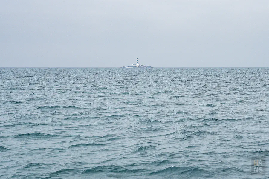 從遊艇上遠眺矗立於玄武岩礁上具有黑白條紋的目斗嶼燈塔