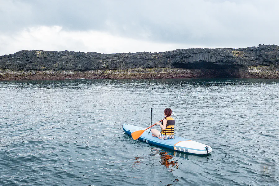 遊客正自在地在鐵砧嶼壯觀的岩洞前體驗SUP立槳樂趣